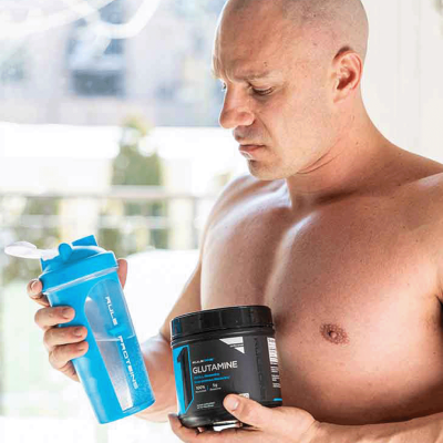 Image of a shirtless man holding a shaker and a container of glutamine